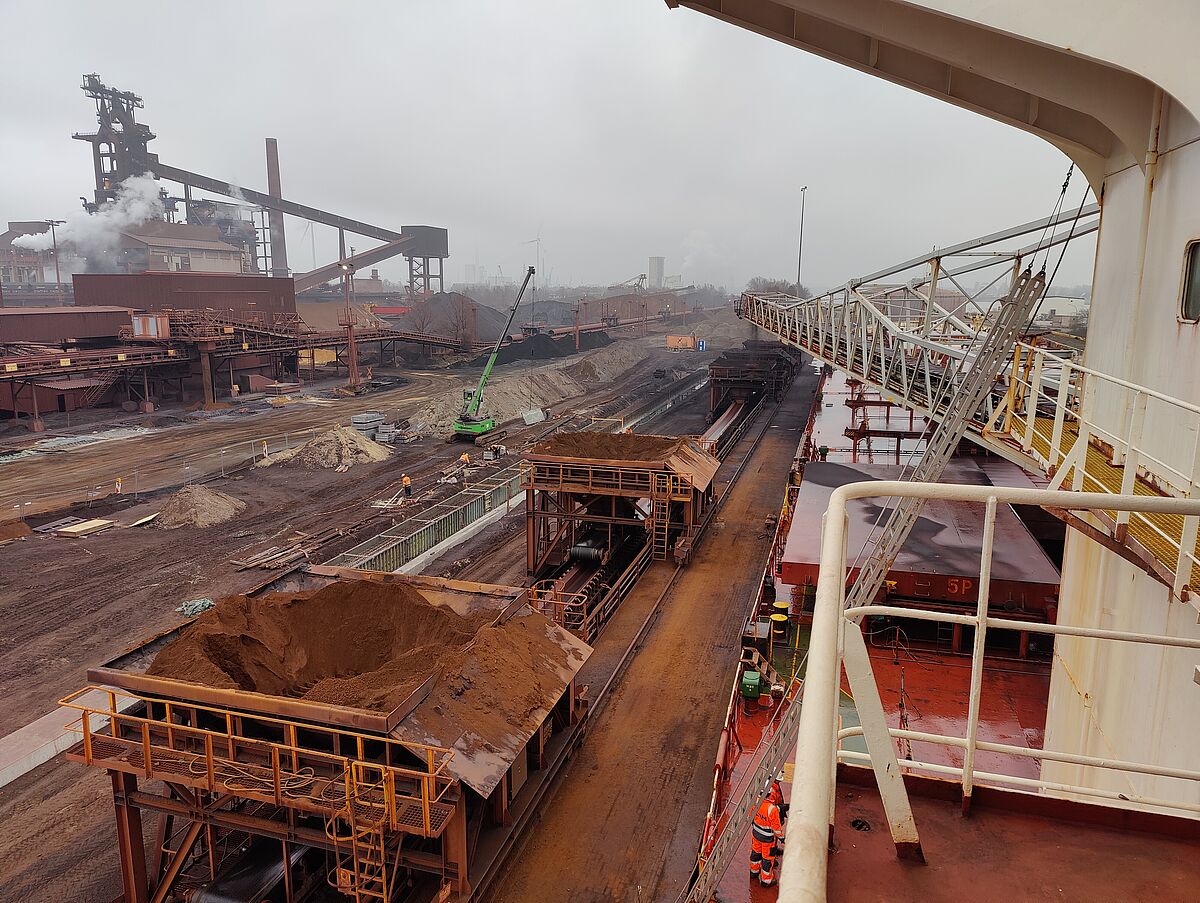 Blick auf die industrielle Umgebung. Das Schiff liefert Eisenerz an das nebengelegene Stahlwerk.